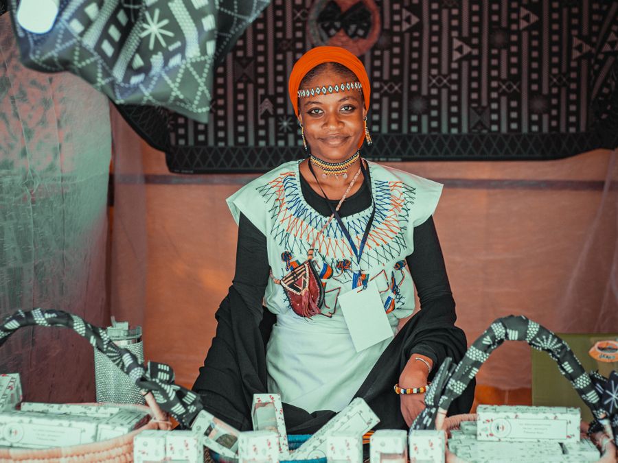A boutique vendor smiling among her goods at a colourful market stall